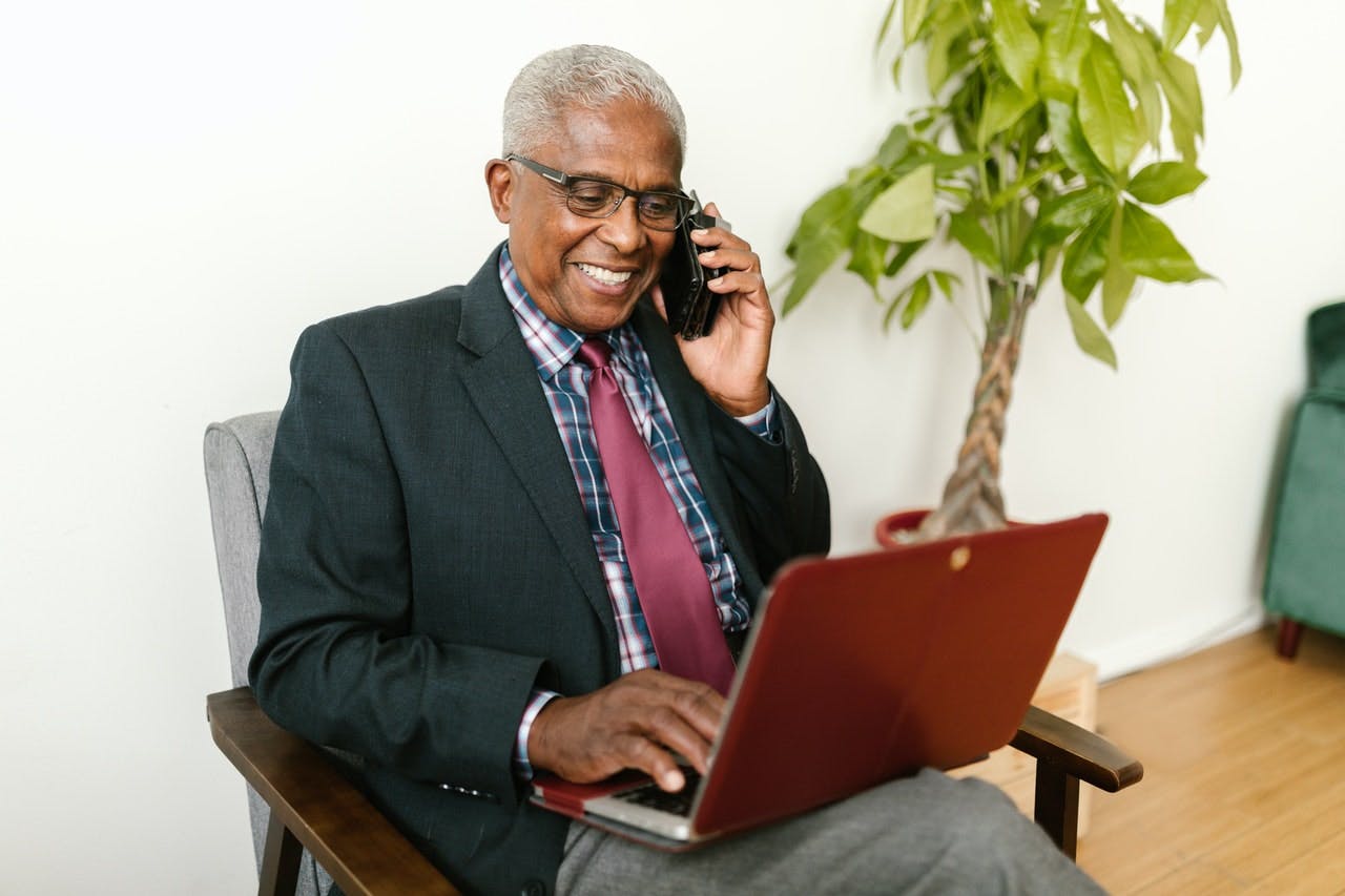 Does Medicare Cover Dental Implants - man smiles while looking at laptop computer and talking on phone.jpg